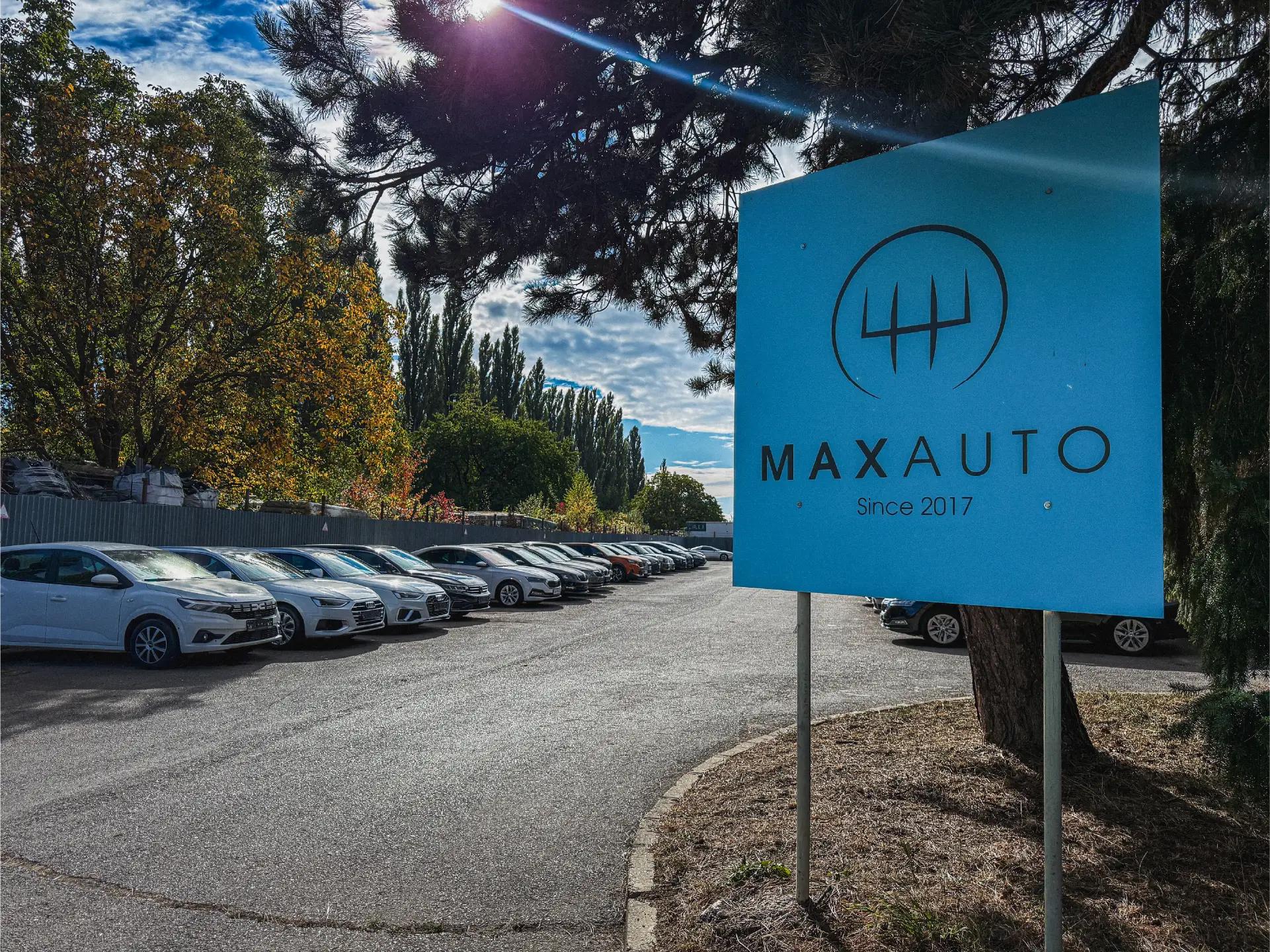 Modrá tabuľa Maxauto pri parkovisku s autami